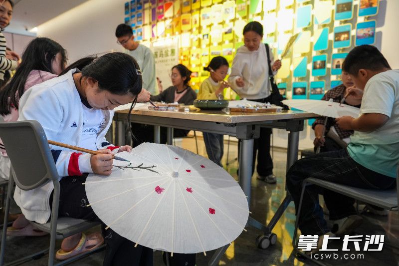 青少年拿起画笔,在油纸伞上勾勒水墨花卉。 青少年拿起画笔,在油纸伞上勾勒水墨花卉。