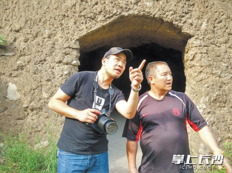 云南禄劝县金沙江皎平渡，本报特派记者(左)在毛泽东住过的山洞前采访纪念馆工作人员。
