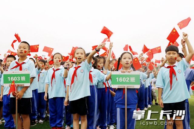 开学典礼上，孩子们激动地挥舞着手中的小国旗。周秋燕 摄