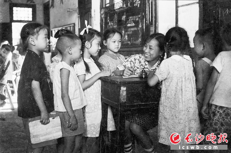 1956年7月28日，长沙市从该年秋季开始实施普及小学义务教育，各小学校采取了随报随考的方式，招收学龄儿童入学。这是一年级的新生在鱼塘街完全小学报名时，回答老师的问话。