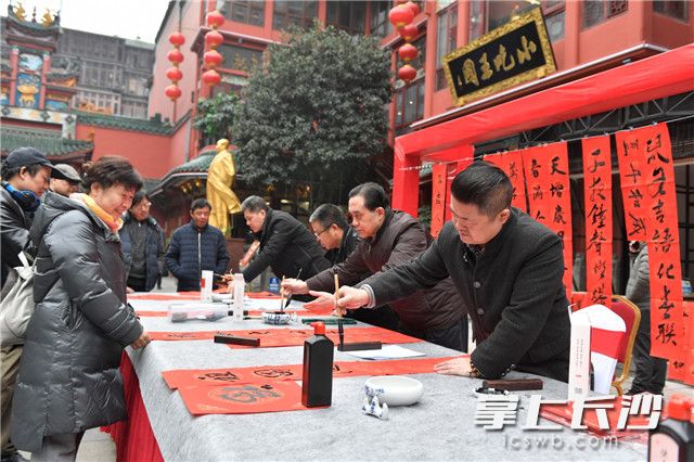 12月30日，“字述湖湘 祝福祖国”2019湖南年度字、公益新闻事件发布活动在长沙火宫殿举行，书法家们正在写春联，免费赠送给市民。
