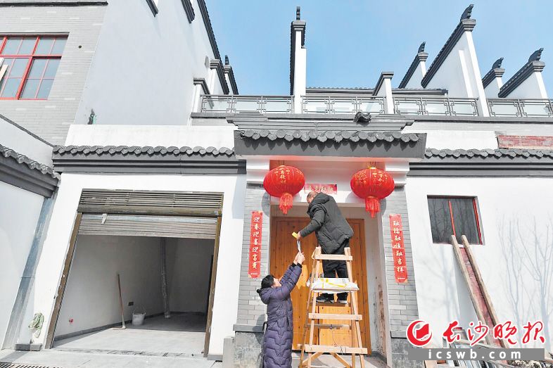 20日上午，长沙县浔龙河生态艺术小镇内，柳建君和贺彩珍夫妇忙着给新家贴春联。长沙晚报全媒体记者 王志伟 摄