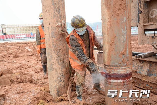 在桩基施工作业区，工人给两根管桩接口处刷上防锈漆以防生锈。岑军 摄