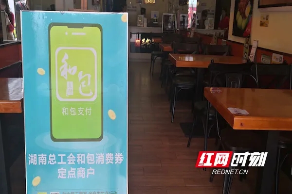 街边煲仔饭店门口提醒客户可使用省总工会和包消费券支付。