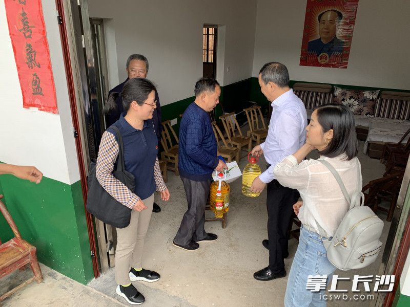 党员干部为农村危改户李新德送上油、米等物资，并参观他的新居