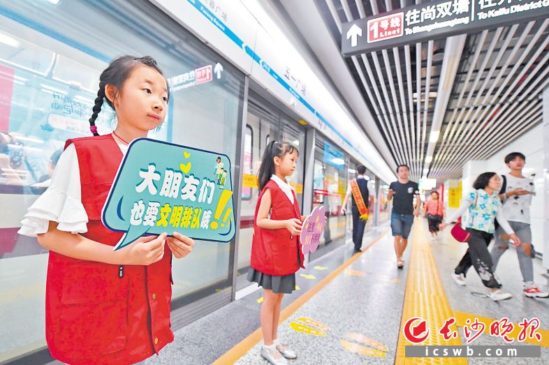 长沙地铁五一广场站内，身穿红马甲的萌娃在地铁工作人员的带领下一同维护车站文明秩序。