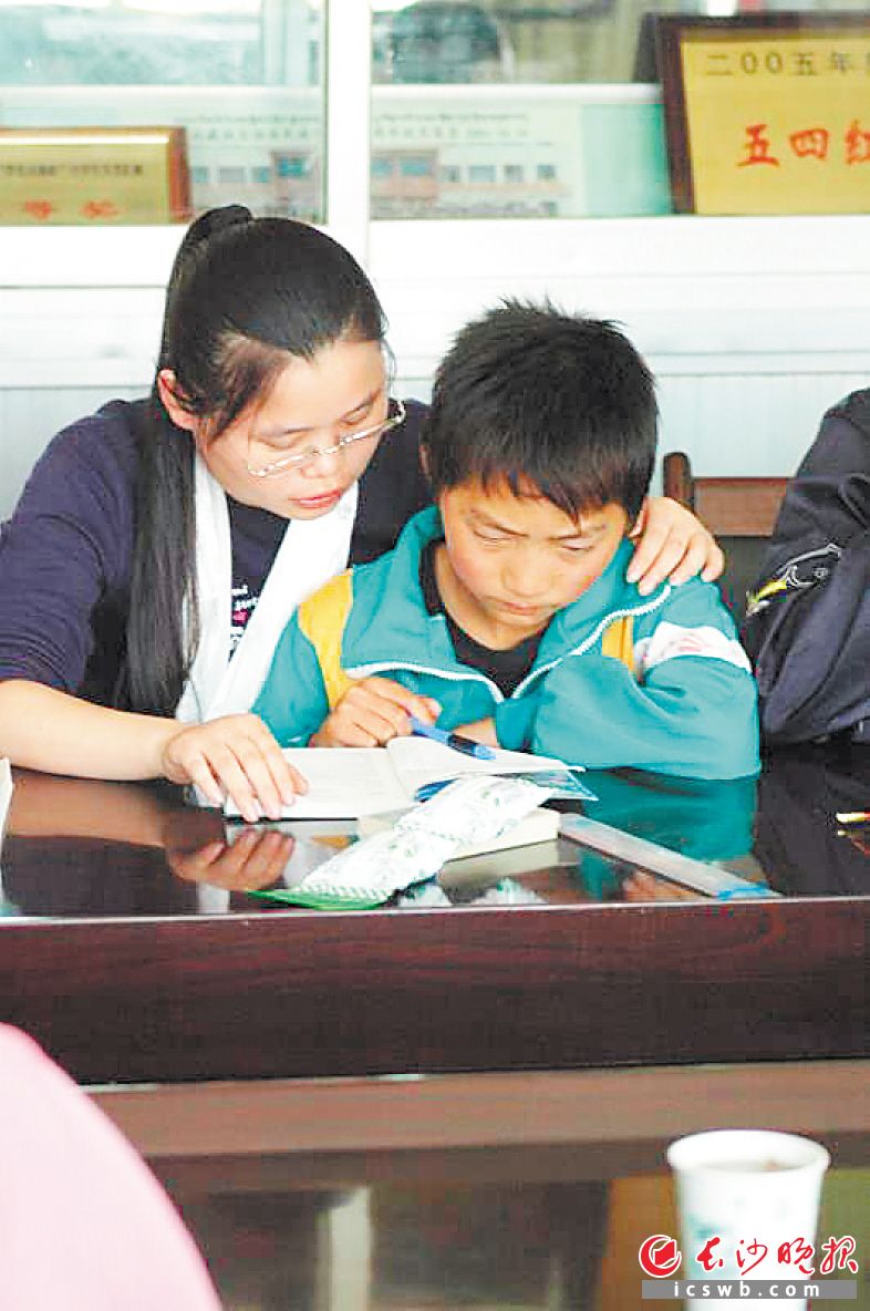 2008年在甘肃助学时，小飞耐心地辅导当地儿童学习。 资料图片