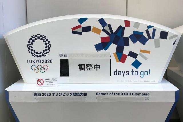 资料图。日本东京中央区，一间写字楼内的原本显示东京奥运会倒计时的电子屏被贴上了“正在调整”，下方奥运会的原定举办日期也被遮挡了起来。