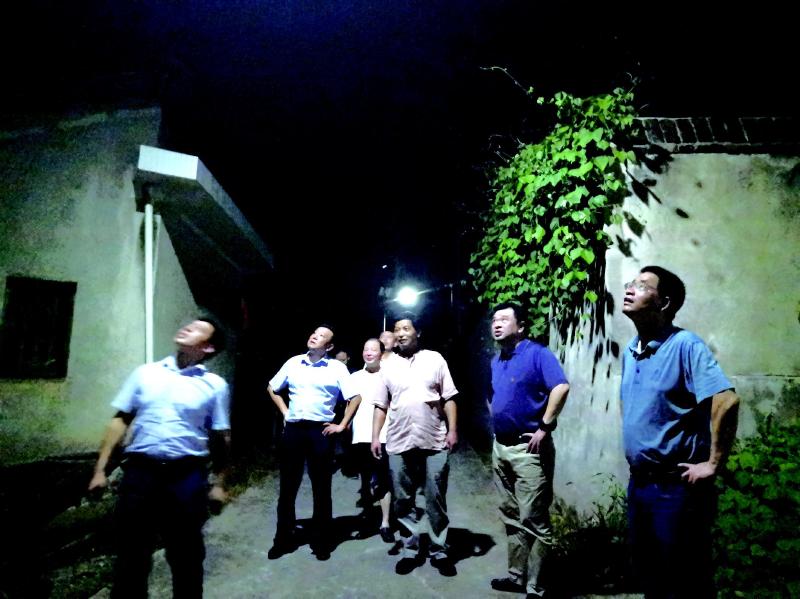 趁着星光，市工建中心党组成员和古城村党总支书记、委员一起走在乡间新修的道路上，边聊边查看路灯照明情况。