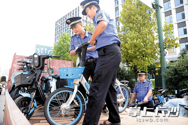 高新区城管执法大队的工作人员将占道违停的共享单车进行清理。吴梦珊 摄