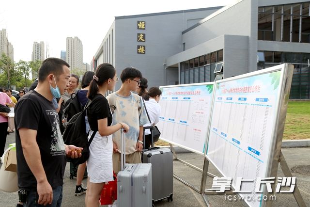 学生和家长查看高一入学考试考场和临时寝室信息公布栏。吴梦珊 摄