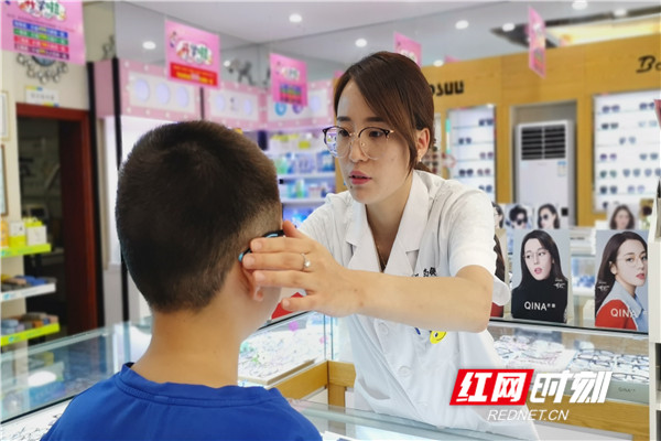 吴亚玲正在给一位顾客调整眼镜镜框。