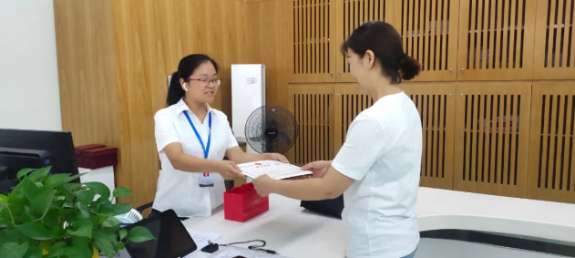 ▲全女士（右一）开心地从行政审批工作人员（左一）手中接过营业执照及免费赠送的公章。