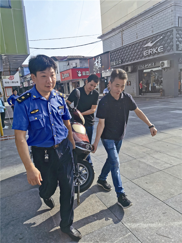 市场服务中心工作人员正在对违停摩托车进行搬移。