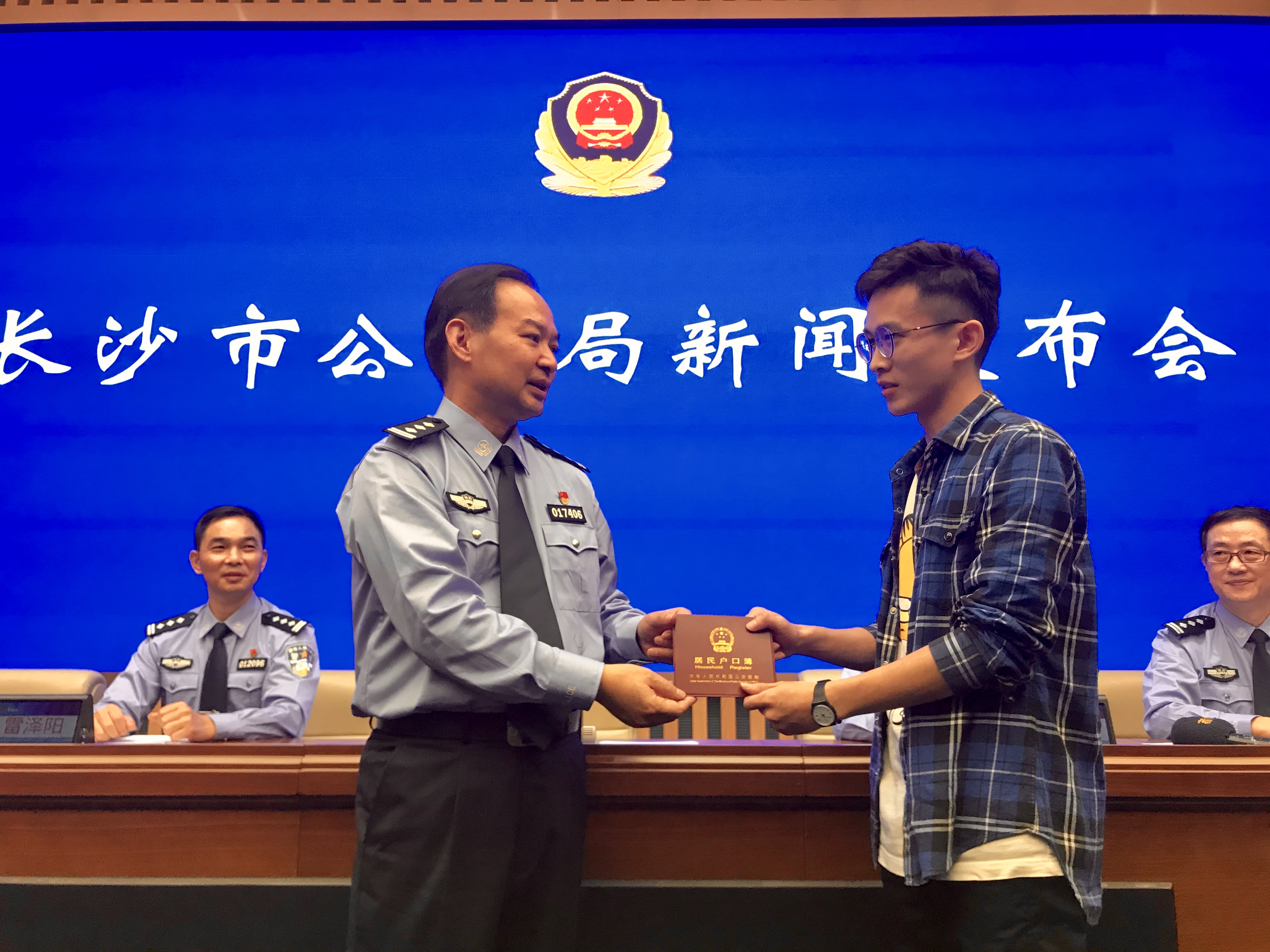 长沙市公安局人口与出入境管理支队支队长刘辉为居民杨程博发放户口簿，杨程博是长沙第一个在网上全流程办理高校职院毕业生落户的居民。长沙晚报全媒体记者 聂映荣 摄