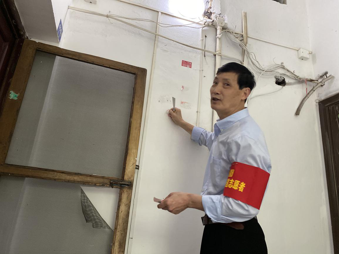 卢圣告在居民楼栋铲除“牛皮癣”。
