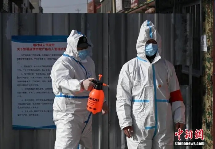 图为警员为从小果庄村出来的防疫工作人员消毒。中新社记者 翟羽佳 摄
