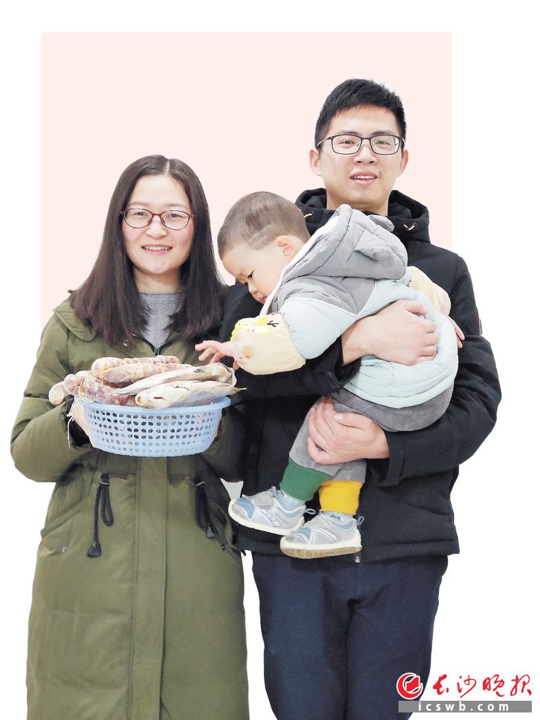 王刘怡、游涛这对湖北夫妻一家今年决定留在长沙过年，手里端着亲人寄过来的香肠、风干鱼