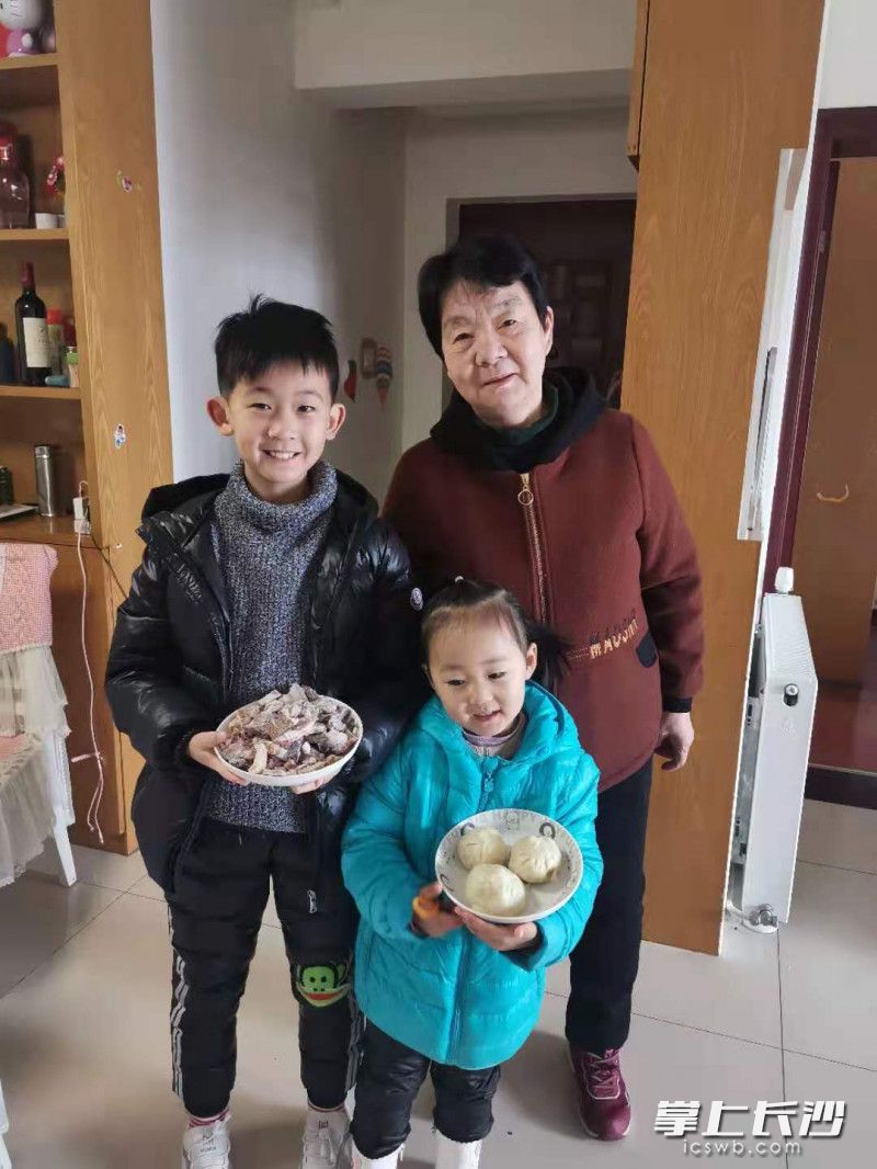 王丽娟的儿子拿的是从河南老家寄过来的羊杂，女儿端着婆婆准备的包子。受访者供图