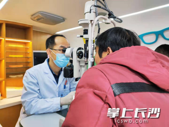 周增超在流动服务车上为邓先生做眼部复查。