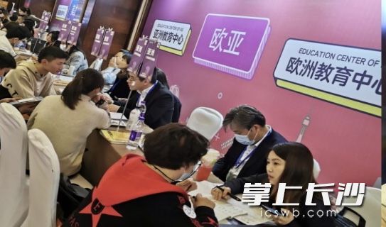 在展台前,家长和孩子一起咨询招生老师。 在展台前,家长和孩子一起咨询招生老师。