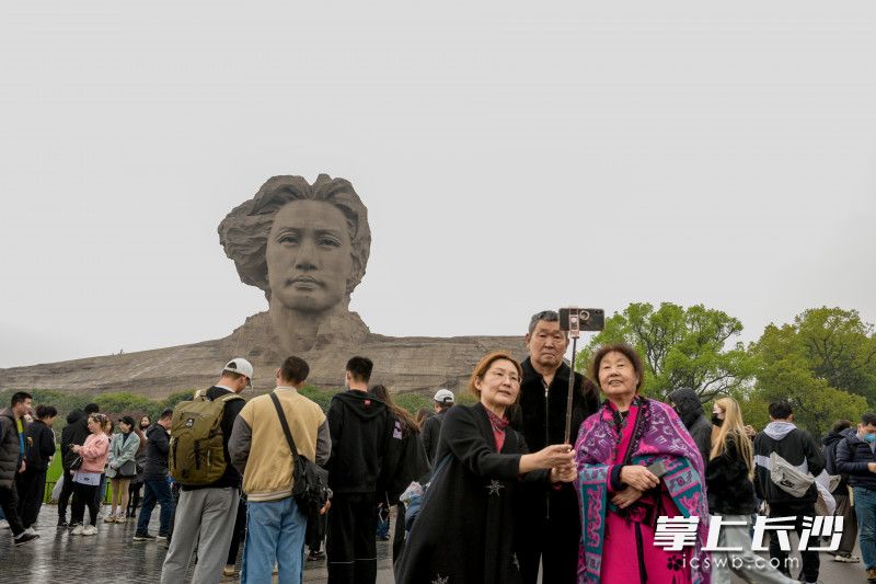 游客与伟人雕塑合影。