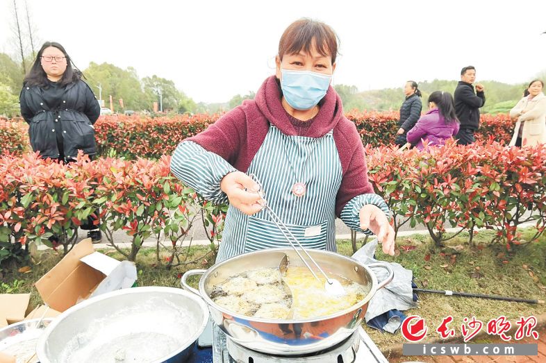 看着花田音乐节引来游人如织，村民欧瑞南连忙亮出自己的好手艺——油炸蒿子粑粑。张禹 摄