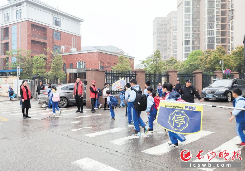 4月7日，长沙高新区雷锋街道党员干部化身红马甲志愿者，护送学生过马路。受访者供图