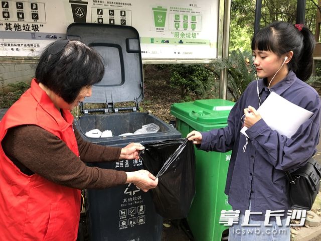 向阳社区涉外花园小区志愿者桶边指导居民将垃圾正确分类。