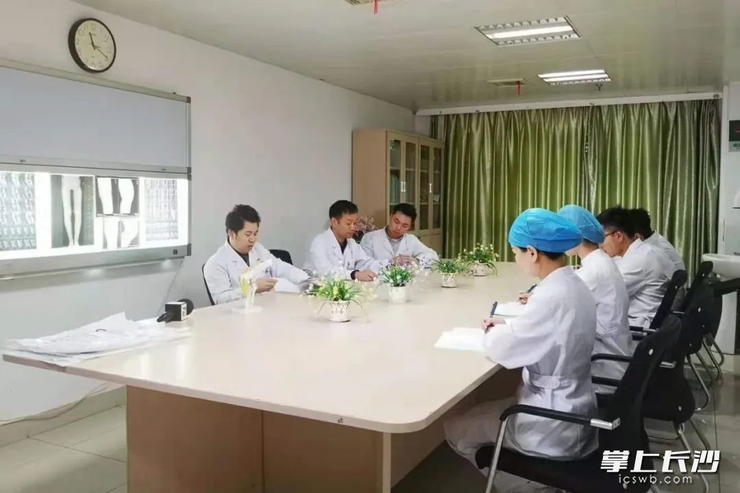长沙市中医医院（长沙市第八医院）骨伤科一病区科主任魏利成带领医护人员讨论治疗方案。  医院供图