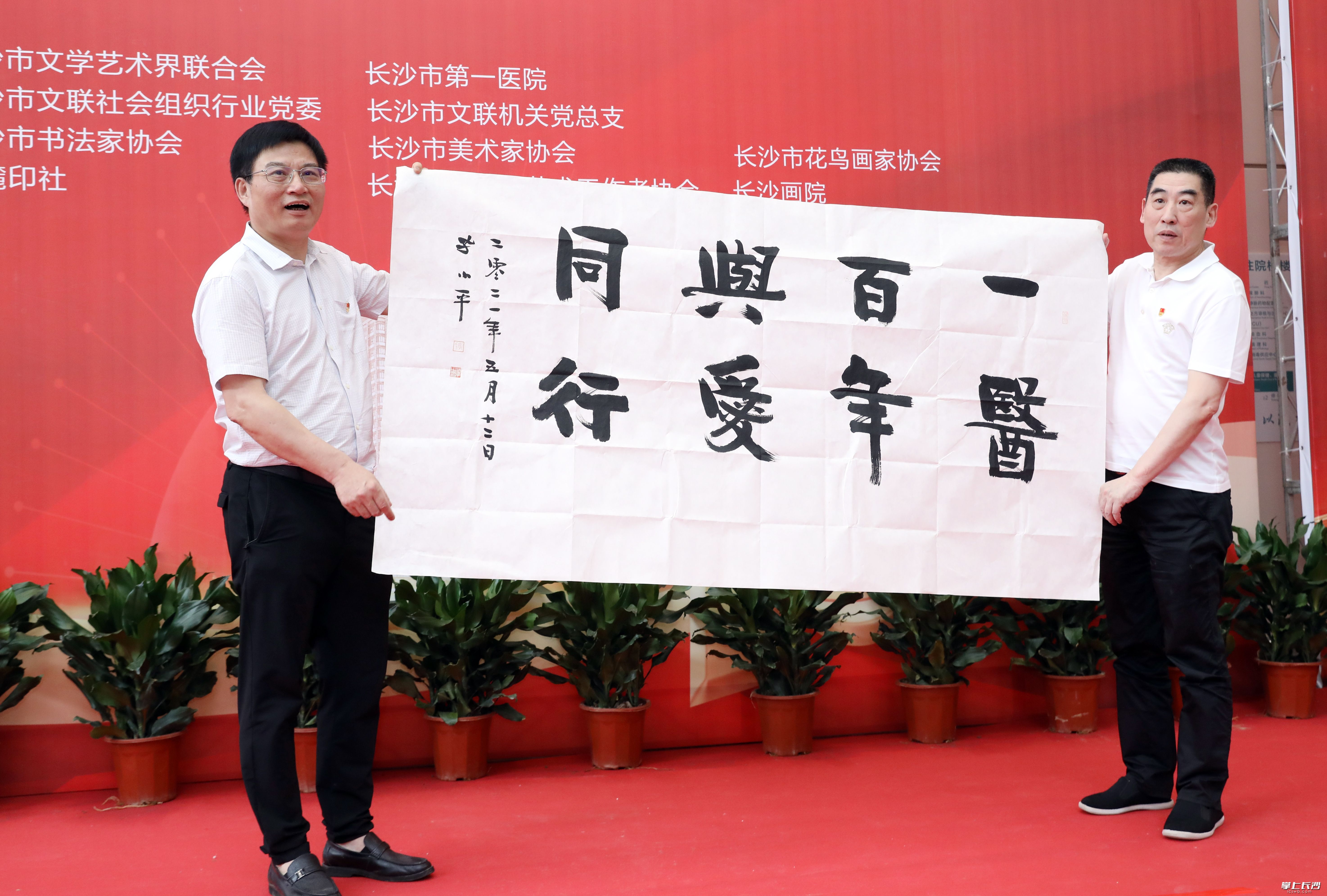 省书法家协会副主席、市书协主席孔小平（右）为长沙市第一医院建院101周年题写“百年一医，与爱同行”。图左为长沙市第一医院党委书记漆晓坚。