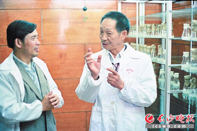 1983年10月　　袁隆平在杂交水稻研究中心的实验室里，与同事商讨繁殖育种的技术问题。
