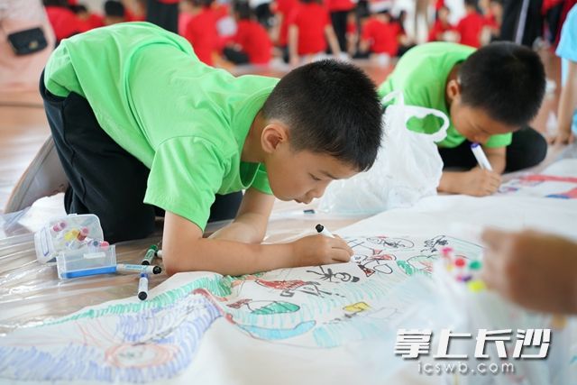 孩子们在长长的画布上用心绘画着属于自己的中国梦。
