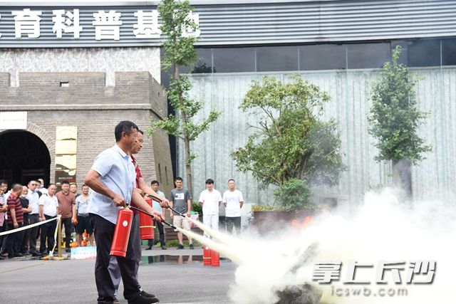 居民代表在专业人员的指导下正确使用灭火器。