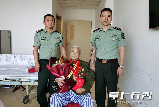 省军区长沙第五干休所负责人探望住院老干部，并为其颁发“光荣在党50年”纪念章。