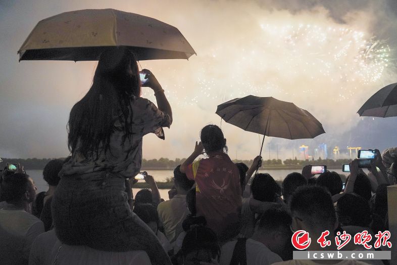 市民坐在同伴肩上，力图拍出最美的焰火“大片“。