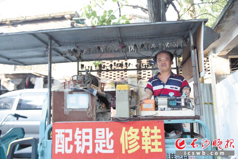 陈建华站在自己的小三轮车上，为新老顾客修鞋配钥匙。长沙晚报全媒体记者 刘琦 摄