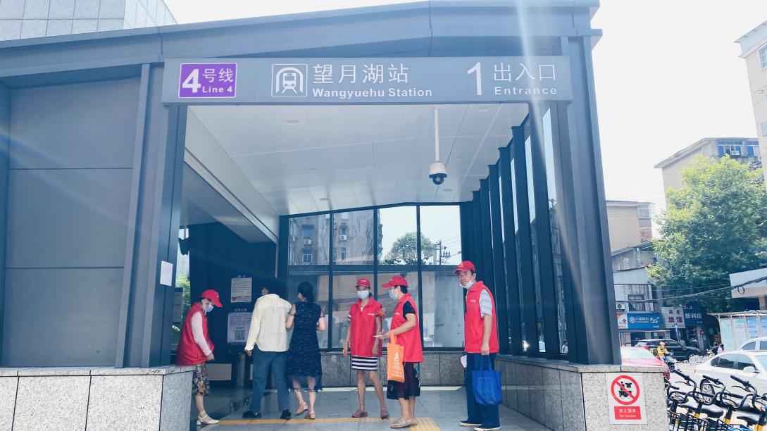 志愿者在地铁4号线望月湖站发放防疫宣传册。