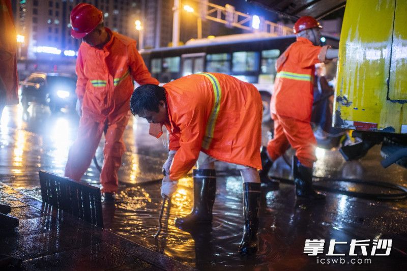 工作人员用铁钩疏通排水口