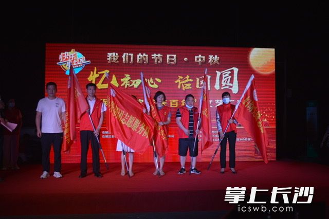为志愿者团队授旗。