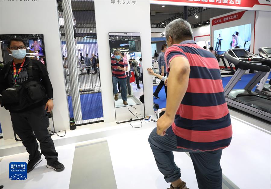 2021年5月19日，一名参观者在上海举行的2021中国国际体育用品博览会上体验一款智能魔镜运动辅助产品。新华社记者 方喆 摄