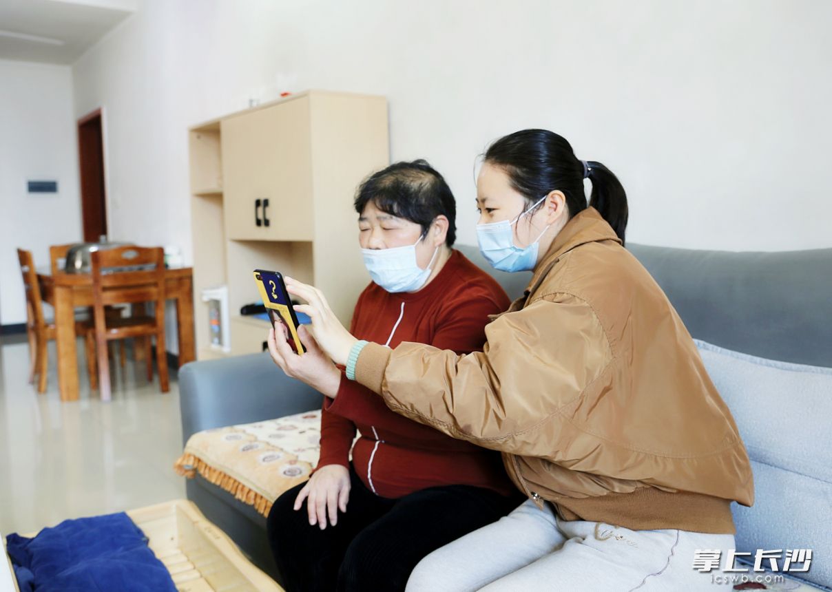 章桂芝（左）通过手机给街道办事处工作人员介绍“兑奖”的相关情况。长沙晚报全媒体记者 颜开云 摄