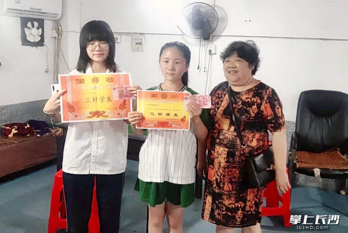 小区一对姐妹同时拿了三好学生，带着奖状来找章桂芝“兑奖”。受访者供图