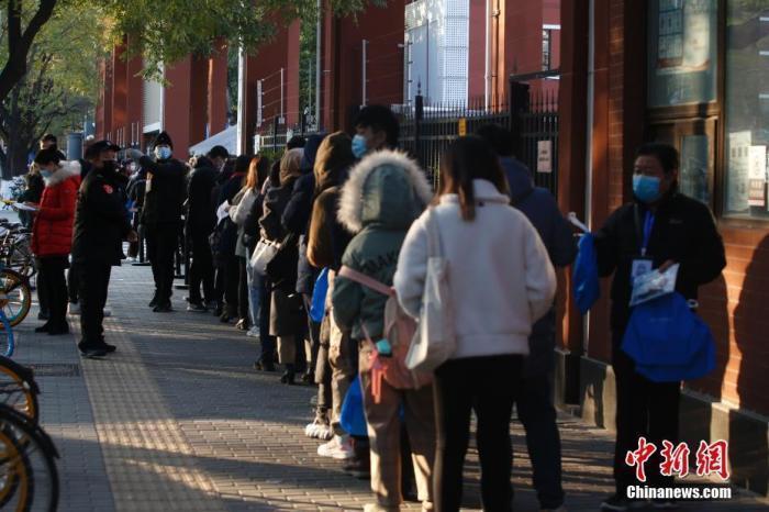 资料图：公务员考试考场外，工作人员核验考生信息
