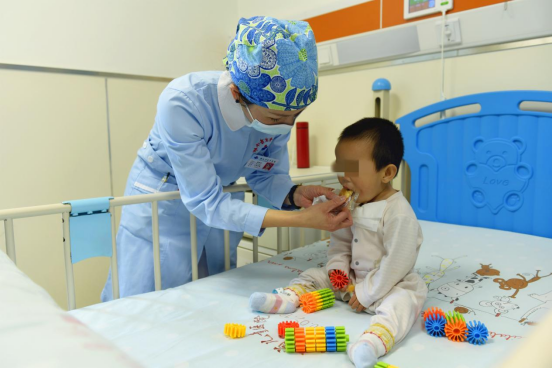 临时妈妈、湖南省儿童医院心胸外科护士长杨贵红给萱萱喂小面包，甜甜的滋味，萱萱最喜欢。长沙晚报通讯员 姚家琦摄