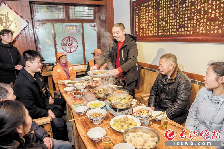雨花区德馨园社区内，粉面店老板王荣华端来亲手烹制的菜肴，邀请一群同样不回家过年的街坊共品团圆宴。 　　长沙晚报全媒体记者 陈飞 摄