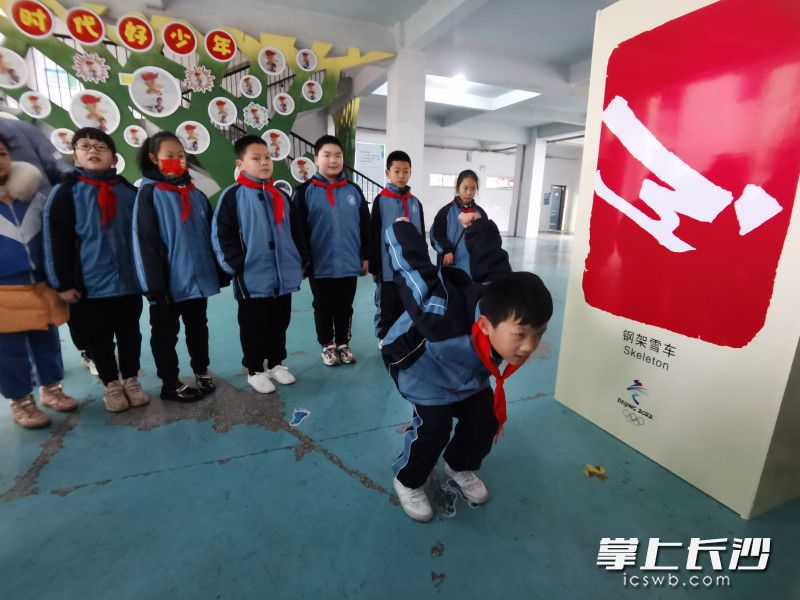 四（8）班学生卓驰轩在体育老师的指导下，模仿起了钢架雪车运动，样子有模有样。