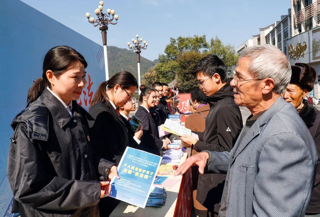 2021年11月12日，景宁畲族自治县鹤溪河畔，工作人员在向过往群众宣传个人信息保护法。图/中新社发 李肃人 摄