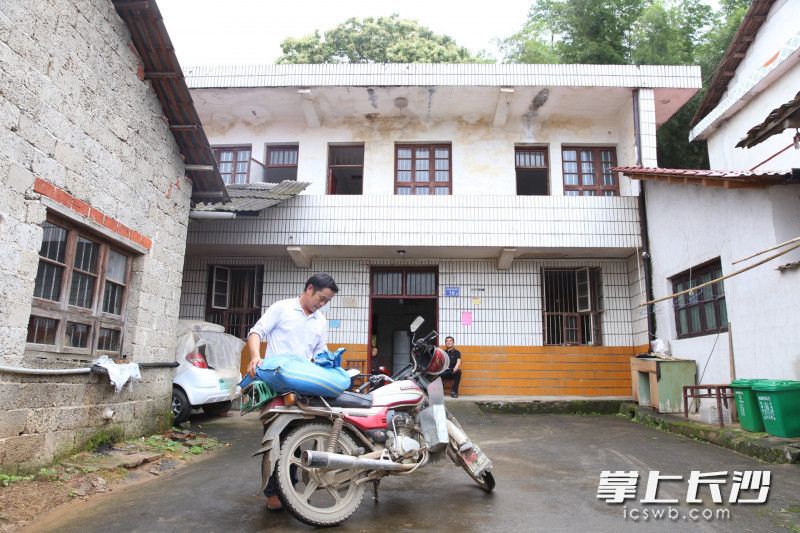 周万千从外面碾米回来，搬进新家后，骑摩托进出都方便多了，以前住山坡上，只有一条泥泞小道出入。长沙晚报全媒体记者 颜开云 摄