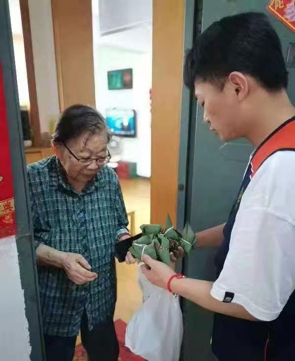 端午节将至，爱心人士将包好的粽子送到社区老人手中。